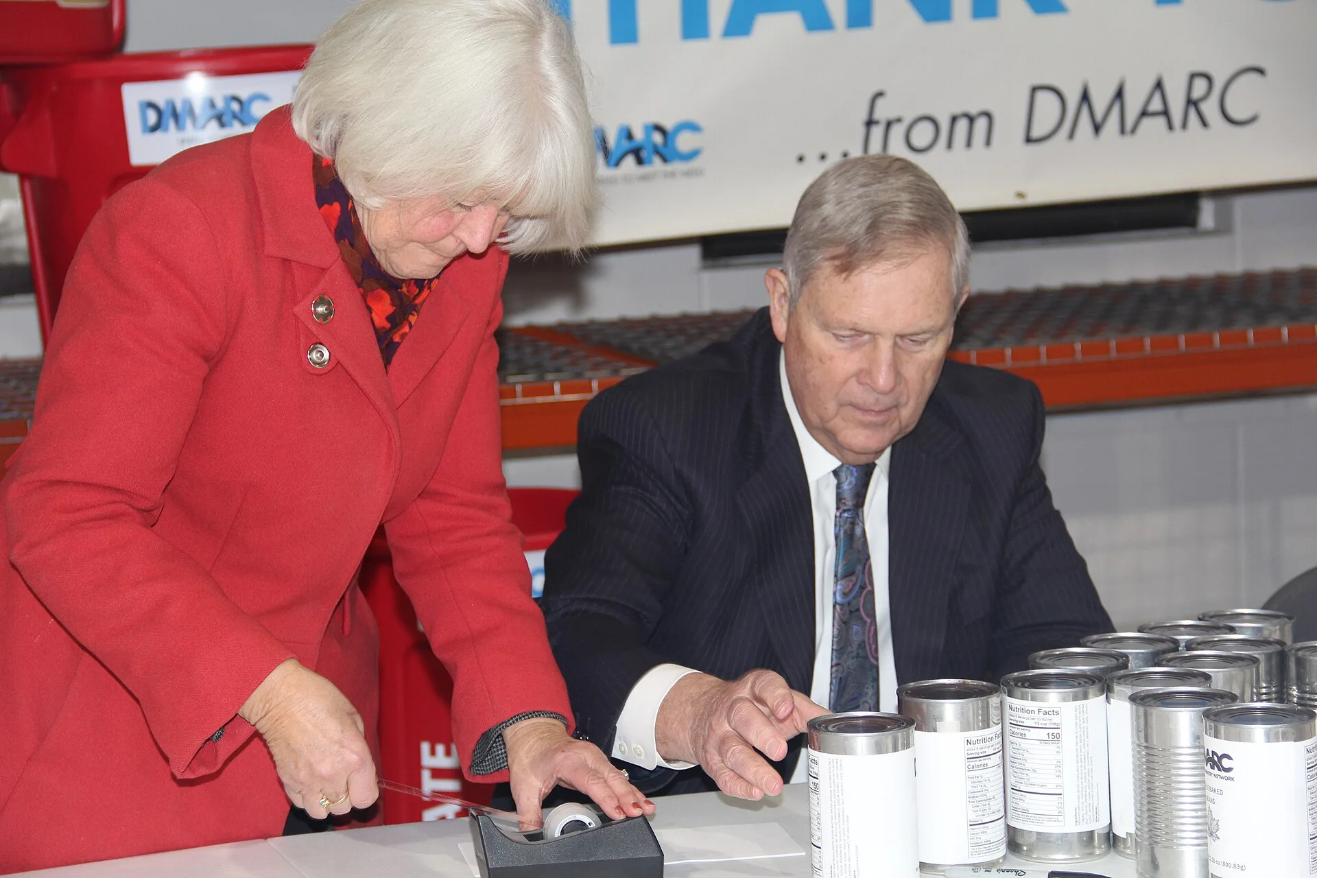 U.S. Department of Agriculture (USDA) Secretary Tom Vilsack and his wife, Christie Vilsack, attach labels to generic cans of beans donated to the Des Moines Area Religious Council (DMARC) – Food Pantry Network warehouse. The Secretary and his spouse toured the facility on the southside of Des Moines. How the FTC treats Made in USA claims on US pantry labels