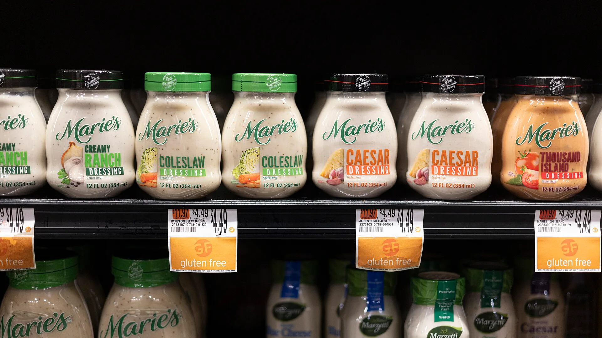 Multiple varieties of Marie’s salad dressing are lined up on a store shelf above price labels and “gluten free” shelf tags. Why gluten-free claims on a specialty food label carry a real number